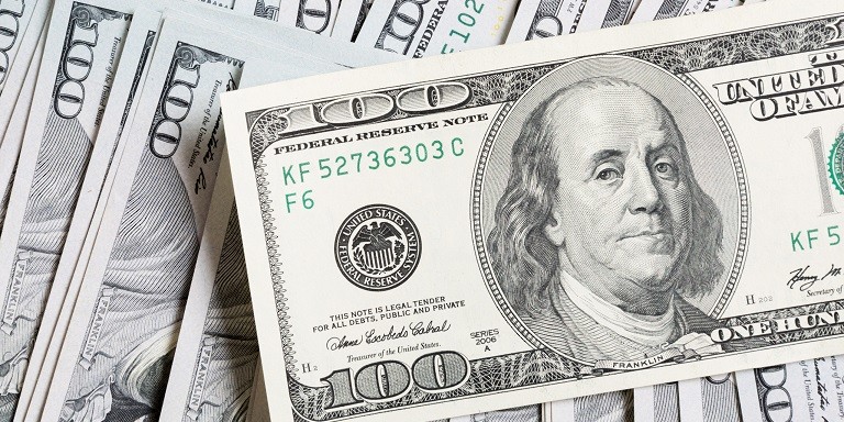 A photo of a stack of $100 bills that focus on Ben Franklin’s picture on one $100 bill.